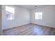Bright bedroom featuring wood-look floors and two windows for natural light at 5653 Artesia Lake Ct, Las Vegas, NV 89118