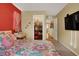 Bright bedroom featuring colorful floral bedding, a red accent wall, and closet view at 759 Star Apple Ln, Las Vegas, NV 89178