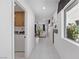 Hallway view featuring white tile flooring and a laundry area, leading to a bright living space at 7977 Texas Hills St, Las Vegas, NV 89113