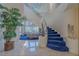 Bright foyer with grand staircase, blue carpeted steps, light tile flooring, and view to living room at 8196 Horseshoe Bend Ln, Las Vegas, NV 89113