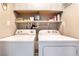 Efficient laundry area with appliances, storage cabinets, and shelving at 8700 Isola Dr, Las Vegas, NV 89117