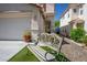 Wooden bench sits in a well-manicured yard adjacent to a home's two-car garage and entry at 8884 Perfect Diamond Ct, Las Vegas, NV 89129