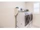 Well-organized laundry room featuring a side-by-side washer and dryer with storage shelves at 9655 Skye Star Ave, Las Vegas, NV 89166