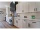 Well-lit kitchen features white cabinets, stainless steel appliances, light wood floors and eye-catching backsplash at 9705 Standard Ave, Las Vegas, NV 89129
