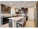 Kitchen features a large island with seating, granite counters, dark wood cabinets, and stainless appliances at 9846 Sunriver Meadows Ave, Las Vegas, NV 89148