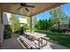 Covered outdoor patio with a ceiling fan, dining table set, barbecue and a well-maintained lawn at 10749 Turquoise Valley Dr, Las Vegas, NV 89144
