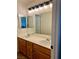 Bright bathroom features dual sinks, wood cabinets, large mirror, and modern lighting fixtures at 1921 Moonlight Bluff Ave, North Las Vegas, NV 89084