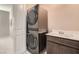 Modern laundry room with stacked washer and dryer next to a sink and vanity at 2507 Silent View Ave, Henderson, NV 89044