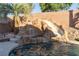Inviting pool featuring a rock waterfall and slide surrounded by lush landscaping at 2549 Sundew Ave, Henderson, NV 89052