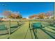 Well-kept tennis court with a green surface, benches, and a secure fence for recreational enjoyment at 3632 Red Fir St, Las Vegas, NV 89135