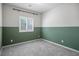 This carpeted bedroom features a half painted green wall and a window at 393 Mullen Ave, Henderson, NV 89044