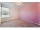 Bright bedroom with neutral carpet, large window, and a pink accent wall at 4610 Lime Straight Dr, Las Vegas, NV 89115