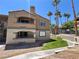 Two-story condo features stucco, balconies, and lush tropical landscaping at 5260 Mission Monterey Ln # 208, Las Vegas, NV 89107