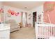 Adorable Bedroom featuring a crib, recliner, pink accents, and closet with open shelving for organized storage at 561 Fork Mesa Ct, Henderson, NV 89015