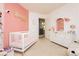 Charming Bedroom featuring a pink accent wall, crib, dresser, and a comfortable recliner with natural lighting at 561 Fork Mesa Ct, Henderson, NV 89015