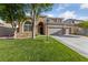 Front exterior of a two-story tan home with manicured lawn, mature trees, and a three-car garage at 5823 Falling Stream Ave, Las Vegas, NV 89131