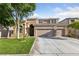 Front exterior of a tan two-story home with manicured lawn, three-car garage, and mature trees at 5823 Falling Stream Ave, Las Vegas, NV 89131