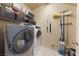 Functional laundry room equipped with a washer, dryer, shelving, and cleaning supplies at 5823 Falling Stream Ave, Las Vegas, NV 89131