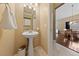 Bright powder room featuring a pedestal sink, decorative mirror, and views into adjacent dining and living areas at 5823 Falling Stream Ave, Las Vegas, NV 89131