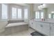 Spa-like bathroom with a soaking tub beneath a bay window, dual sinks, and a large mirror at 6131 Rio Vista St, Las Vegas, NV 89130