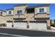Three-story condo with individual one car garages and neutral colored facade under a bright blue sky at 6170 E Sahara Ave # 1012, Las Vegas, NV 89142