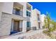 Charming townhome featuring a mix of stucco and stone facade, complemented by a black metal balcony and manicured landscaping at 6288 Dolosonte St, Las Vegas, NV 89113
