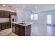 Bright kitchen featuring a quartz island, stainless steel appliances, dark wood cabinets, and an open layout to the living area at 6288 Dolosonte St, Las Vegas, NV 89113