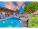 Sparkling swimming pool with rock waterfall feature and covered patio in a serene backyard setting at 7670 Descanso Ln, Las Vegas, NV 89123