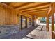 Cozy covered porch featuring stone accents, wood paneling, and brick flooring at 7950 Red Barn Dr, Las Vegas, NV 89123