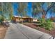 Single-story home with a long driveway, a covered porch, and lush front yard landscaping at 7950 Red Barn Dr, Las Vegas, NV 89123