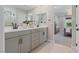 Well-lit bathroom featuring double sinks, modern fixtures, and a view into the bedroom and shower at 7983 Texas Hills St, Las Vegas, NV 89113