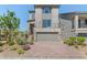 Modern two-story home with a stone facade, landscaped yard, balcony, and brick driveway at 7983 Texas Hills St, Las Vegas, NV 89113
