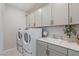 Spacious laundry room with modern appliances, sink, and updated cabinetry at 7983 Texas Hills St, Las Vegas, NV 89113