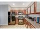 Modern kitchen features wood cabinetry, granite countertops and black appliances at 8717 Red Brook Dr # 201, Las Vegas, NV 89128