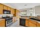 Well-lit kitchen with stainless appliances, wooden cabinets, granite counters, tile floors, and backyard views at 8849 Pheasant Valley Way, Las Vegas, NV 89123