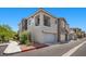 Exterior angle of the modern home with a two-car garage, balcony and a stone facade detail, a sidewalk, and desert landscape at 965 Nevada State Dr # 41201, Henderson, NV 89002
