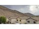 Exterior view of residences showing the neighborhood backing up to a mountain on an overcast day at 10642 Dawns Mist Ave, Las Vegas, NV 89129