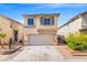 Charming two-story home featuring a two-car garage and low-maintenance desert landscaping under a bright blue sky at 10642 Dawns Mist Ave, Las Vegas, NV 89129