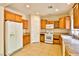 Functional kitchen with wood cabinetry, white appliances, and tiled flooring at 11816 Orense Dr, Las Vegas, NV 89138