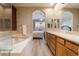 Bright bathroom featuring a soaking tub, double sinks, decorative mirrors, and seamless bedroom access at 1387 Minuet St, Henderson, NV 89052