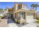 Close up of a two-story tan home with desert landscaping leading to front door and attached garage at 1833 Winners Cup Dr, Las Vegas, NV 89117
