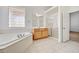 Bright bathroom featuring a large soaking tub, glass block window, and neutral tile floors at 2150 Ponticello Dr, Henderson, NV 89052