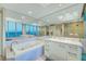 Well lit bathroom with a large window, white cabinets, a tub and mirrors at 222 Karen Ave # 601, Las Vegas, NV 89109