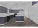 Open kitchen boasts gray cabinets, a center island, modern appliances, and wood-look floors at 2410 Morocco Ave, North Las Vegas, NV 89031