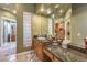 Bathroom featuring double sink vanity with granite countertop, mirrored wall, and glass block accents at 27 Via Paradiso St, Henderson, NV 89011