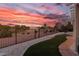 Scenic backyard view with wrought iron fence, desert landscaping, and vibrant sunset at 2816 Golfside Dr, Las Vegas, NV 89134