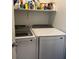 Bright laundry room with modern, white front-loading washer and dryer, as well as convenient shelving at 411 Hellebores Ave, North Las Vegas, NV 89084