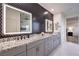 Stylish bathroom featuring black accent wall, dual sinks, and illuminated mirrors at 5328 Hickory Tree St, Las Vegas, NV 89149