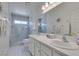 Bright bathroom features a walk-in shower, dual sinks, decorative mirrors, and modern tile floors at 6 Sandwedge Dr, Henderson, NV 89074
