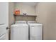 Functional laundry room featuring a washer, dryer, and convenient shelf for storing supplies at 688 Monroe Hill Pl, Henderson, NV 89011